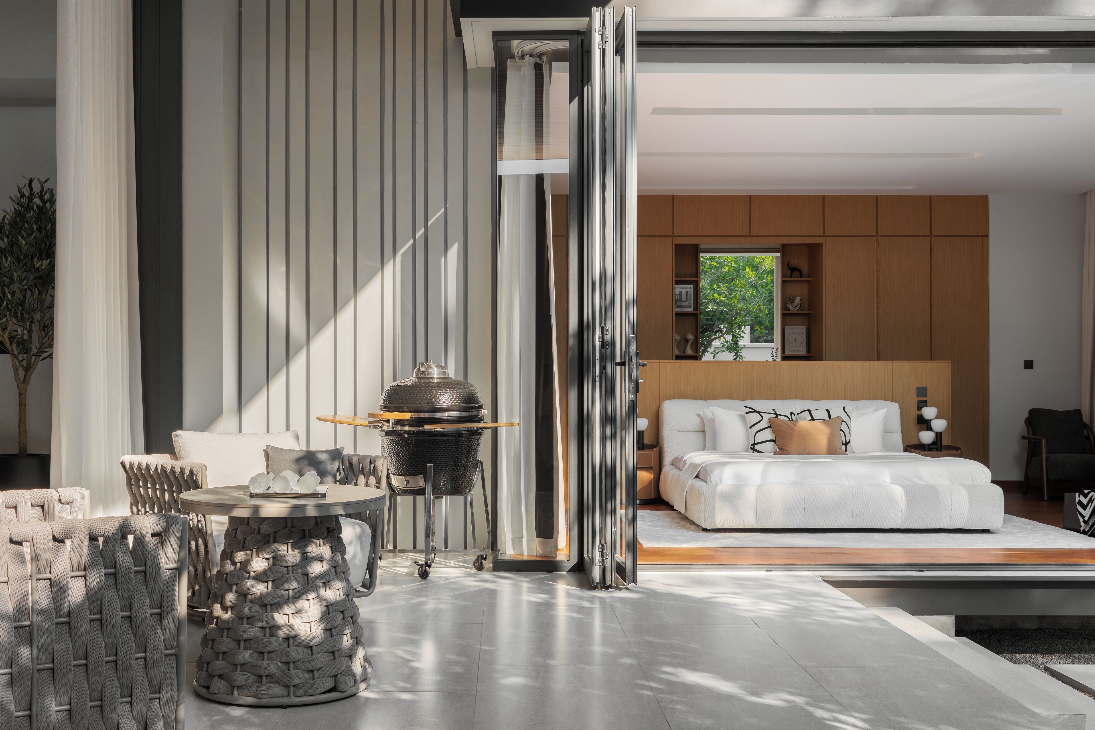 A modern bedroom with a large bed, a bedside table, and a view of a garden.