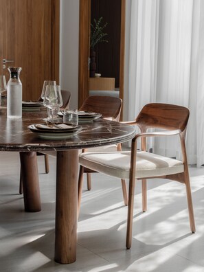 A dining area with a round wooden table, chairs, and a vase. - Layan -10 Min to Beach - Spacious Pool Villa (Thalang District)