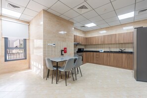 Eine moderne Küche mit Essbereich, ausgestattet mit einer gefliesten Spritzschutzwand, Holzschränken und einem Edelstahlkühlschrank.