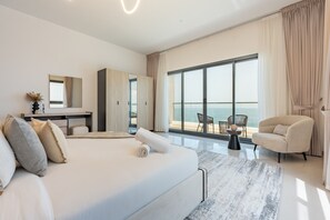 Habitación de hotel moderna con una cama grande, un escritorio, una silla y vistas al mar.