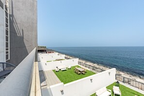 Terraza en la azotea con vistas al mar, amueblada con asientos exteriores y una pequeña zona ajardinada.