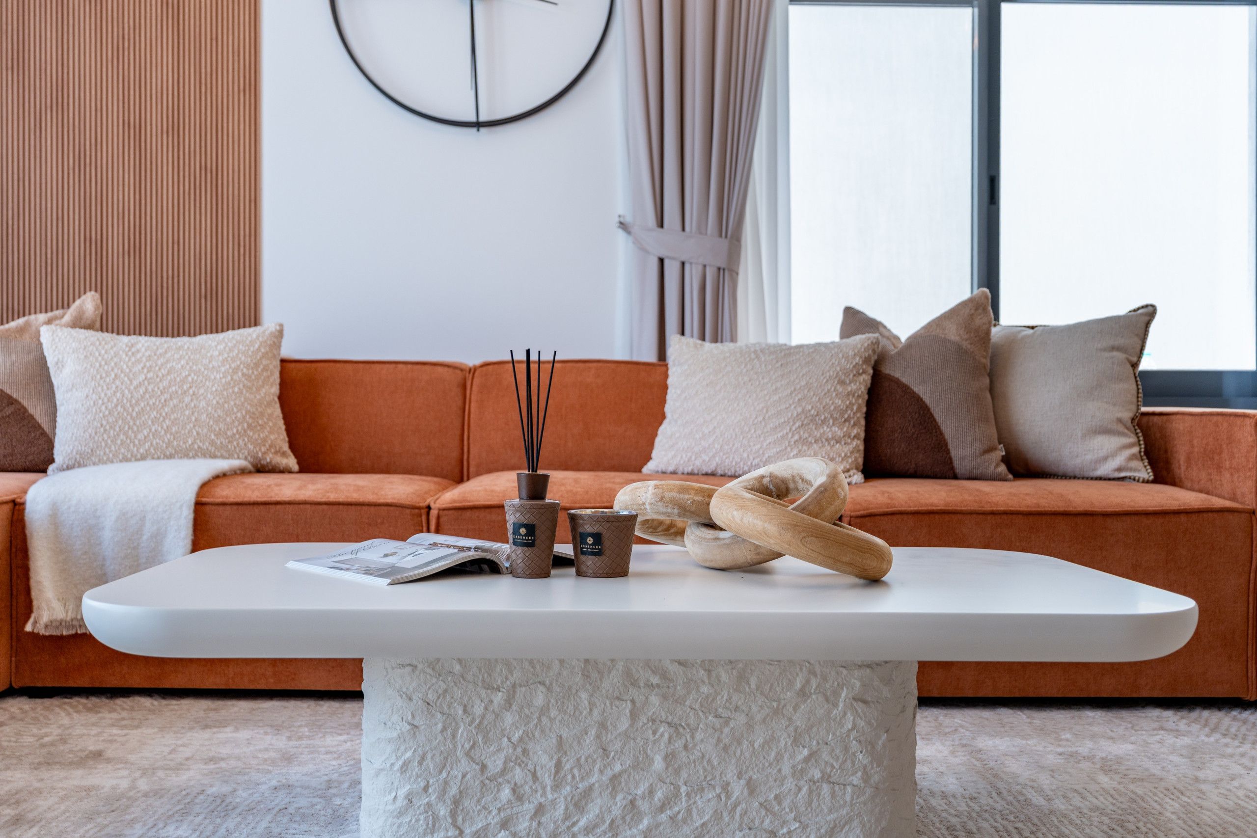 Ein modernes Wohnzimmer mit einer Couch, Kissen, einem Couchtisch und einer Uhr an der Wand.