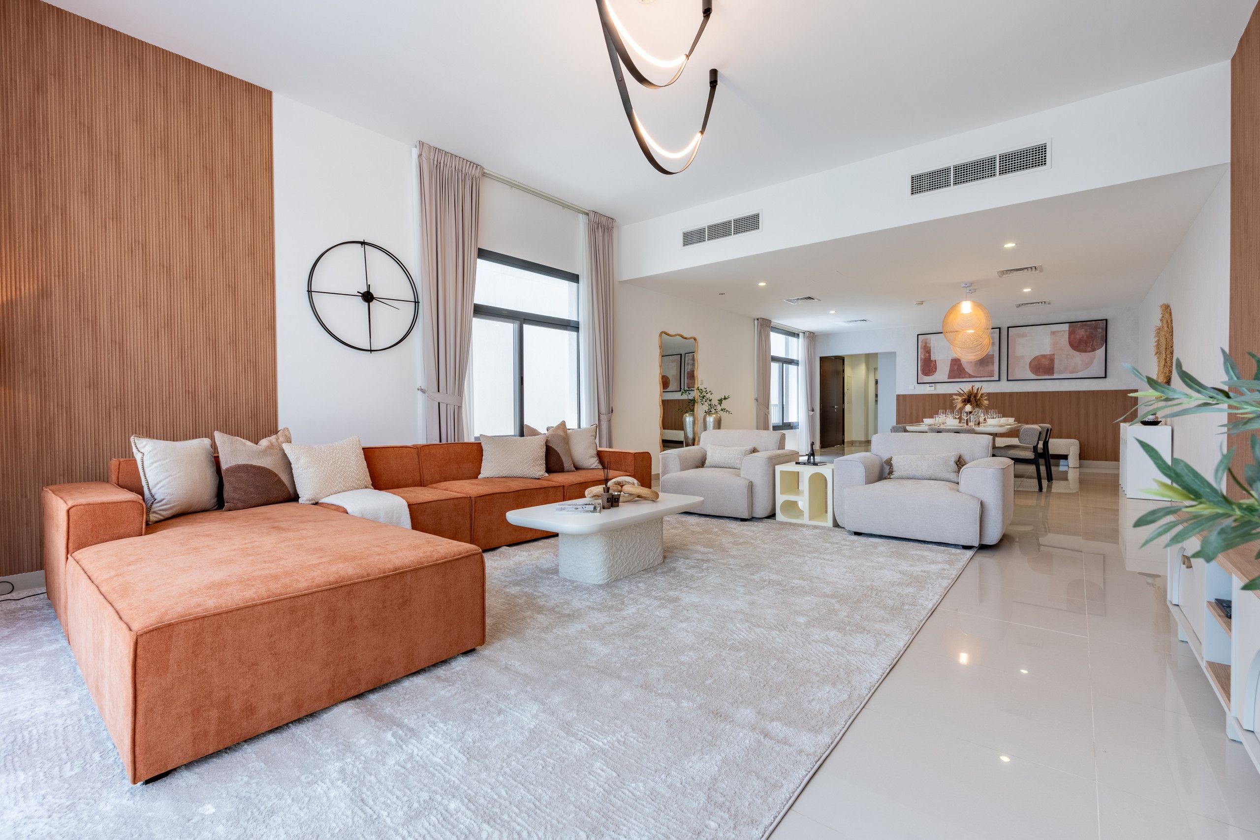 Amplia sala de estar con un sofá seccional grande, una mesa de centro y un comedor con mesa dispuesta para cuatro.