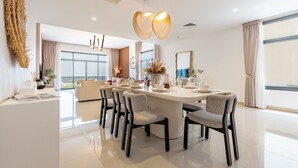 A modern dining area with a round table, six chairs, and a decorative centerpiece. - Contemporary 4BR Villa with Assistant & Driver Rooms, Gulf Views, BBQ and Outdoor Lounge (Fujairah)
