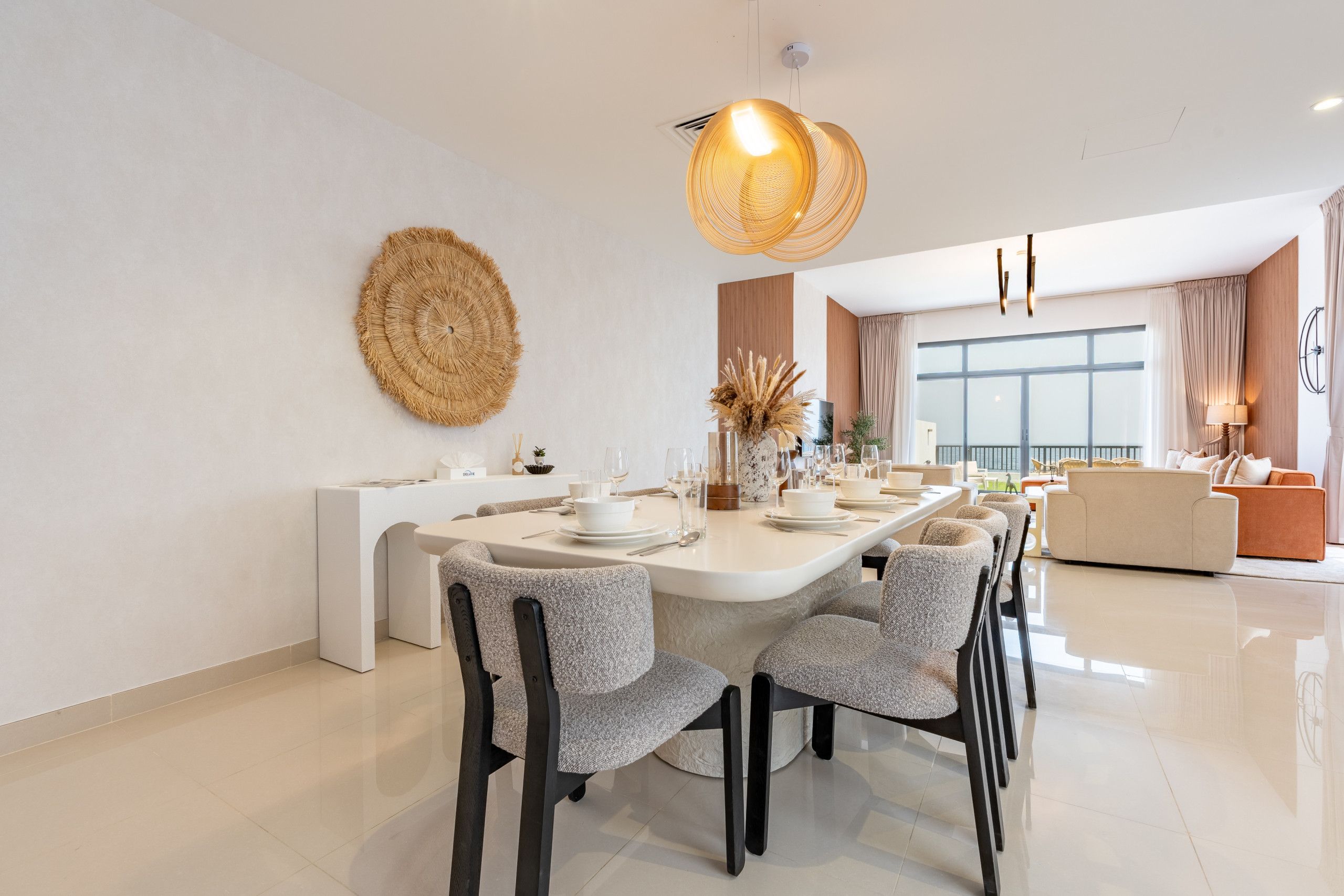 Een moderne eetruimte met een lange tafel, stoelen en een decoratief wandobject.