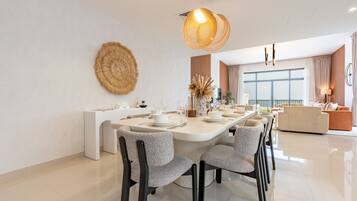 Een moderne eetruimte met een lange tafel, stoelen en een decoratief wandobject.