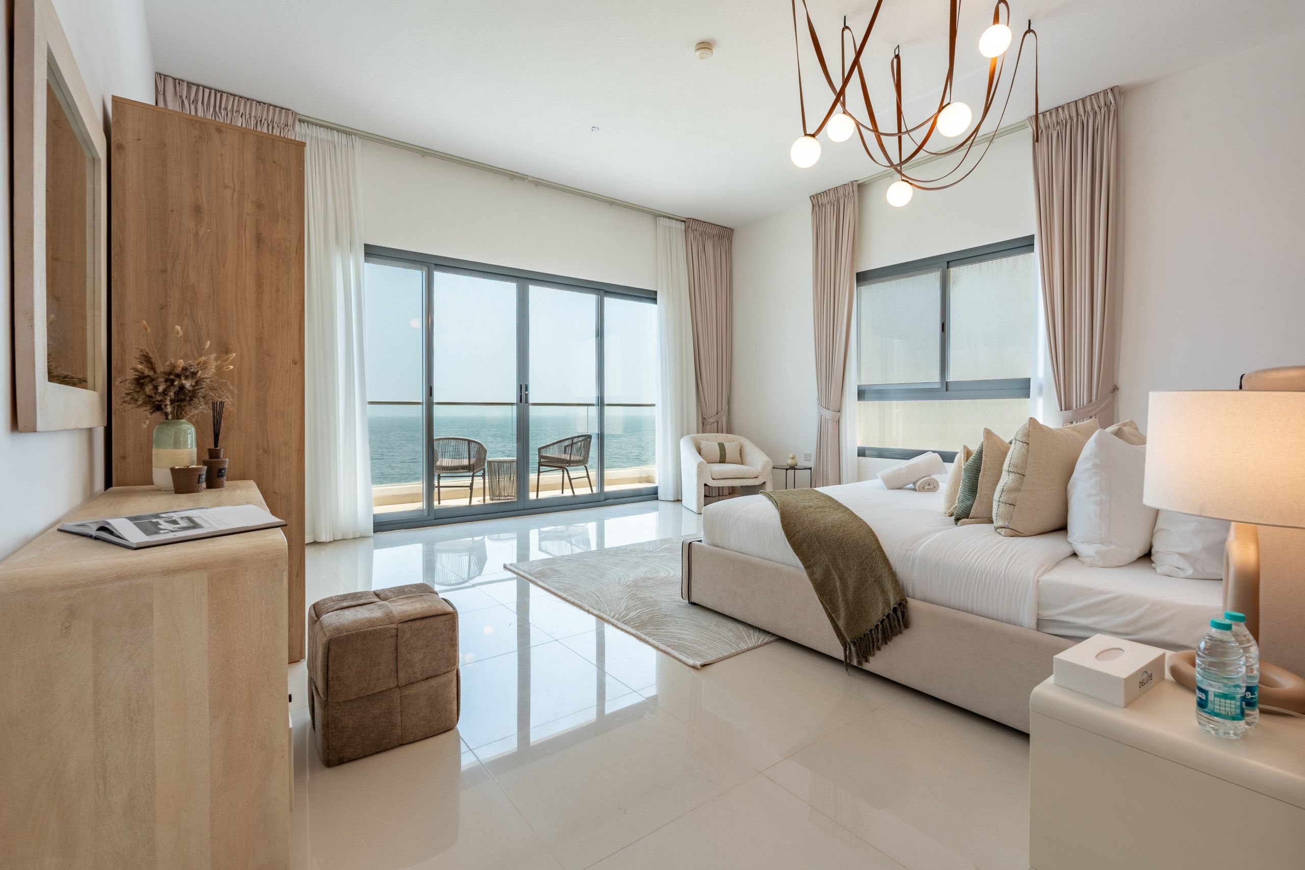 Habitación de hotel moderna con un balcón grande, una cama sofá, un escritorio y vista al mar.