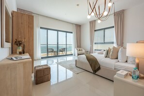 A modern hotel room with a large balcony, a sofa bed, a desk, and a view of the sea. - Contemporary 4BR Villa with Assistant & Driver Rooms, Gulf Views, BBQ and Outdoor Lounge (Fujairah)