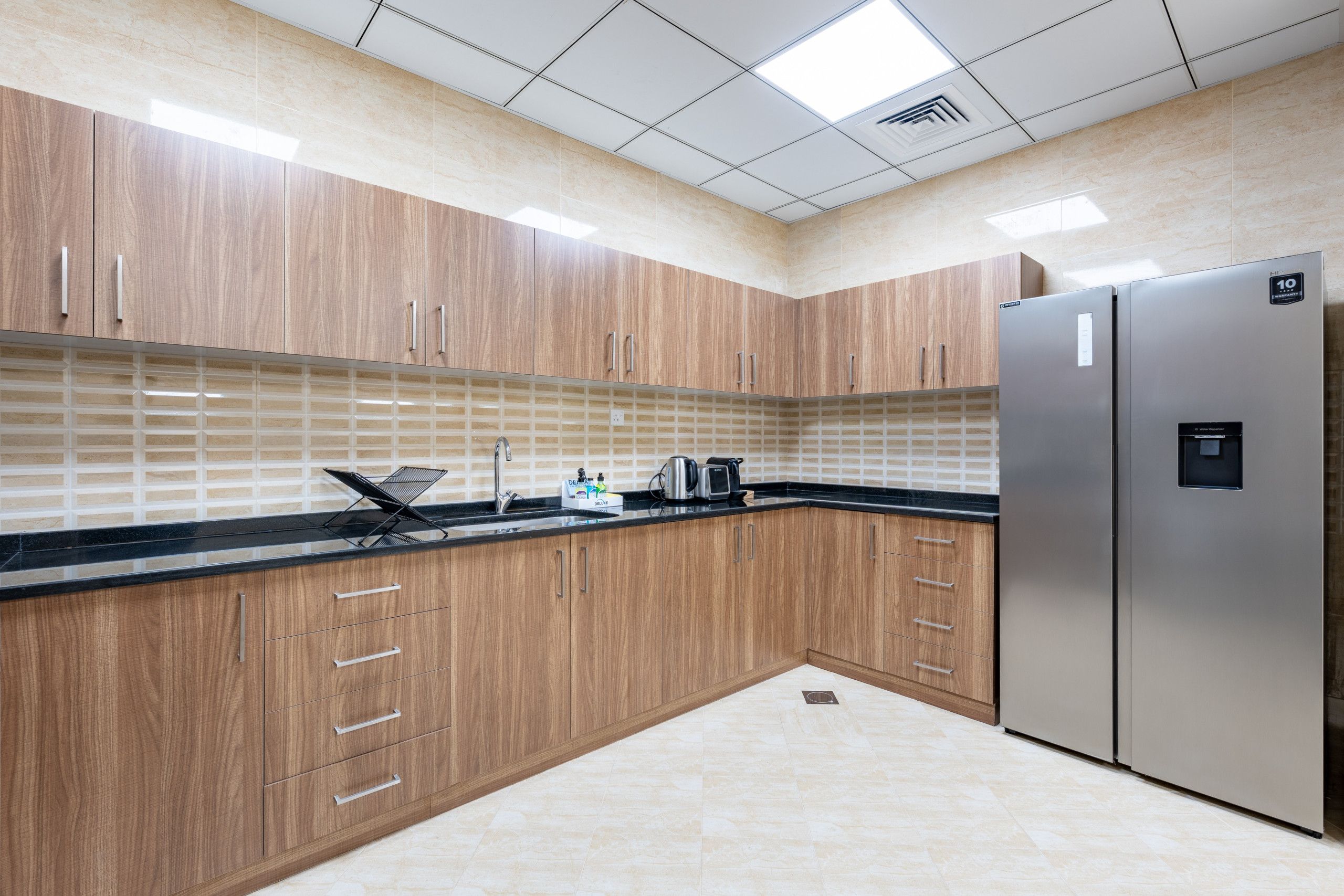 Una cocina moderna con armarios de madera, un refrigerador de acero inoxidable y una encimera negra.