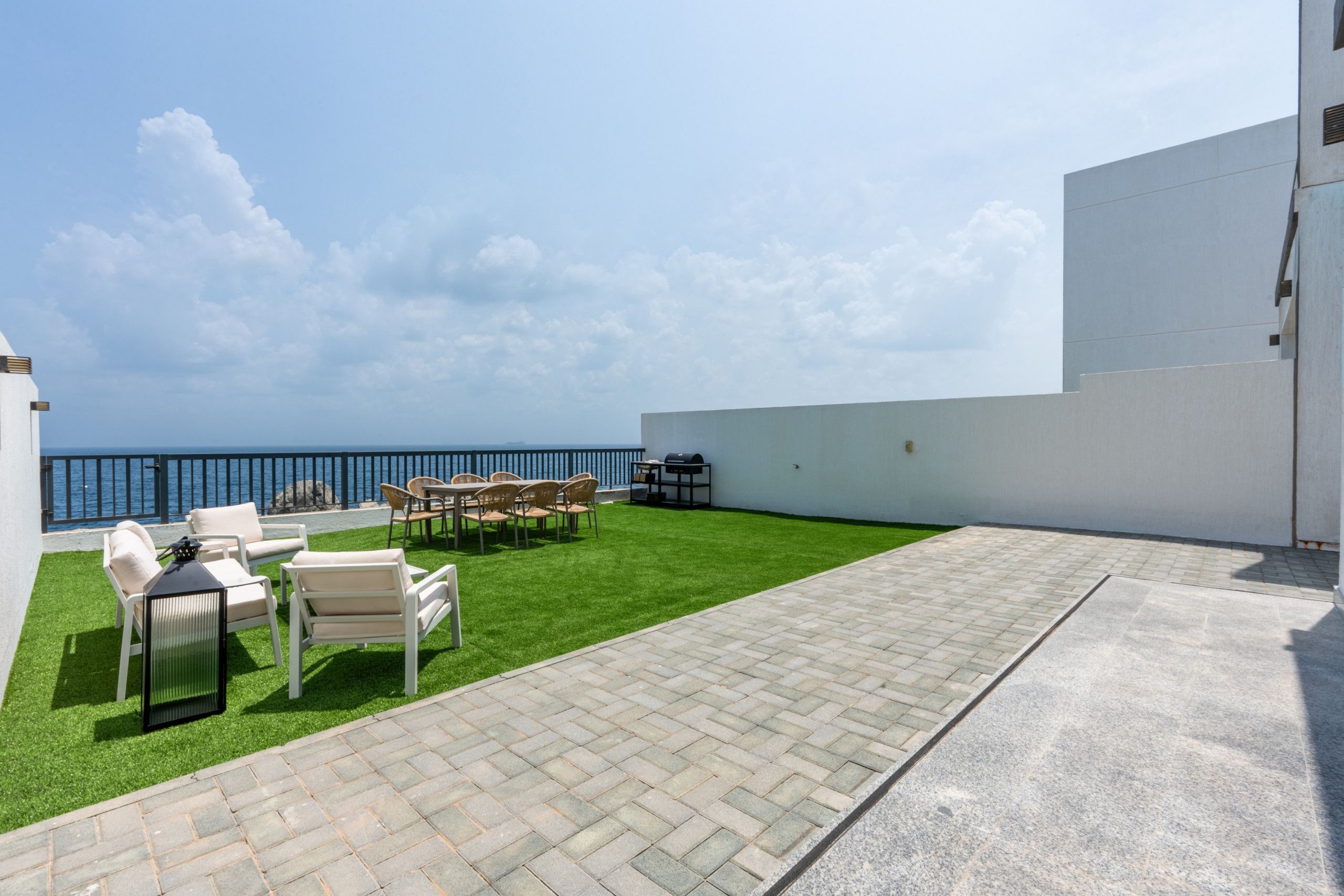 Eine Terrasse mit Gartenmöbeln und Grill, mit Blick auf ein Gewässer.