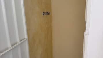 A small, enclosed shower area with a tiled floor and a single drain.