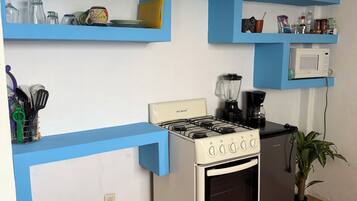 A kitchen with blue shelves, a stove, oven, microwave, and potted plants.