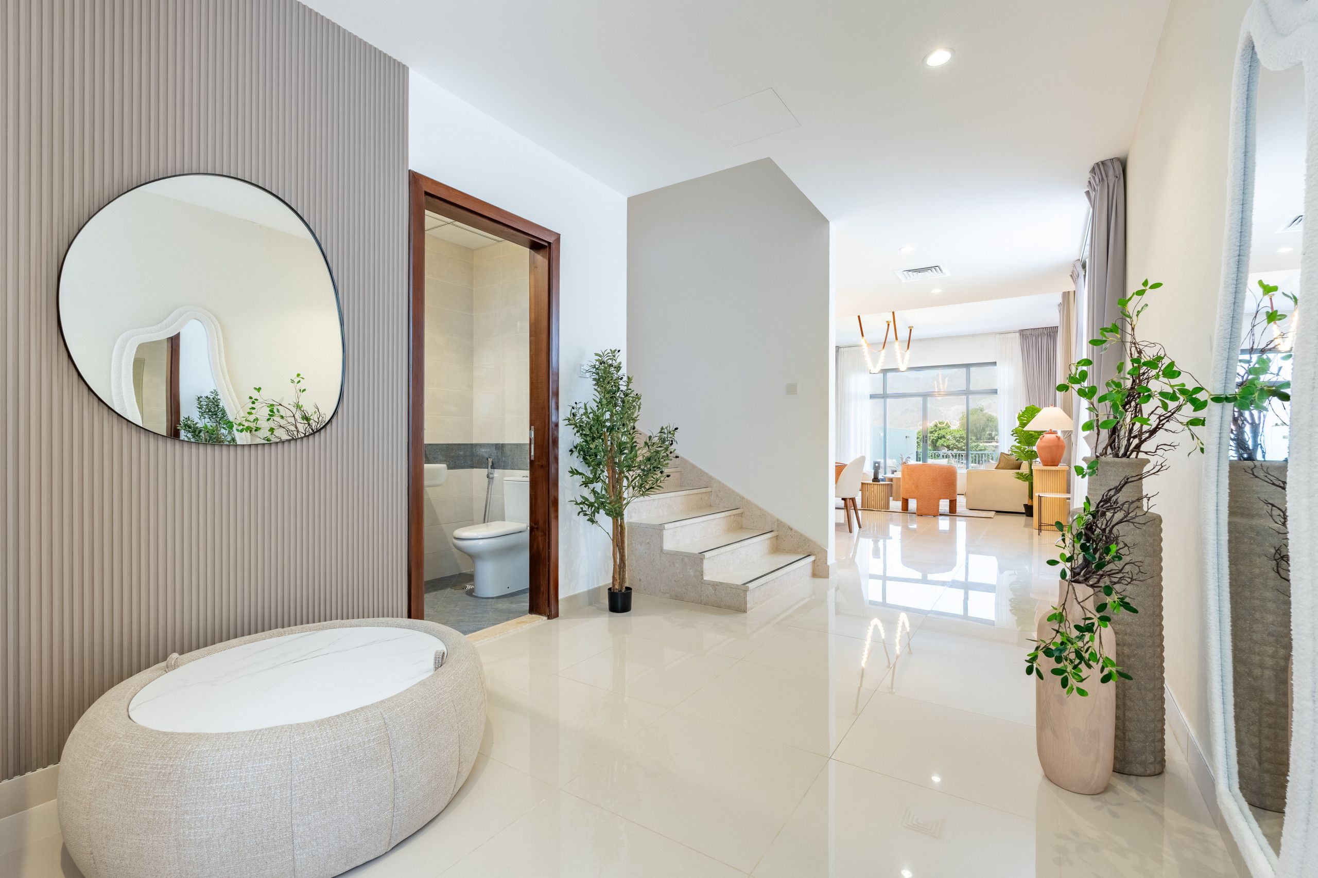Un interior moderno con una bañera redonda, un espejo grande y una escalera que lleva a una sala de estar.