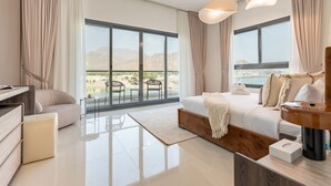Et moderne hotelværelse med en stor seng, et skrivebord og udsigt til en swimmingpool og bjerge.