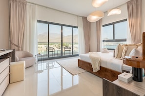 Habitación de hotel moderna con una cama grande, un escritorio y vistas a una piscina y montañas.
