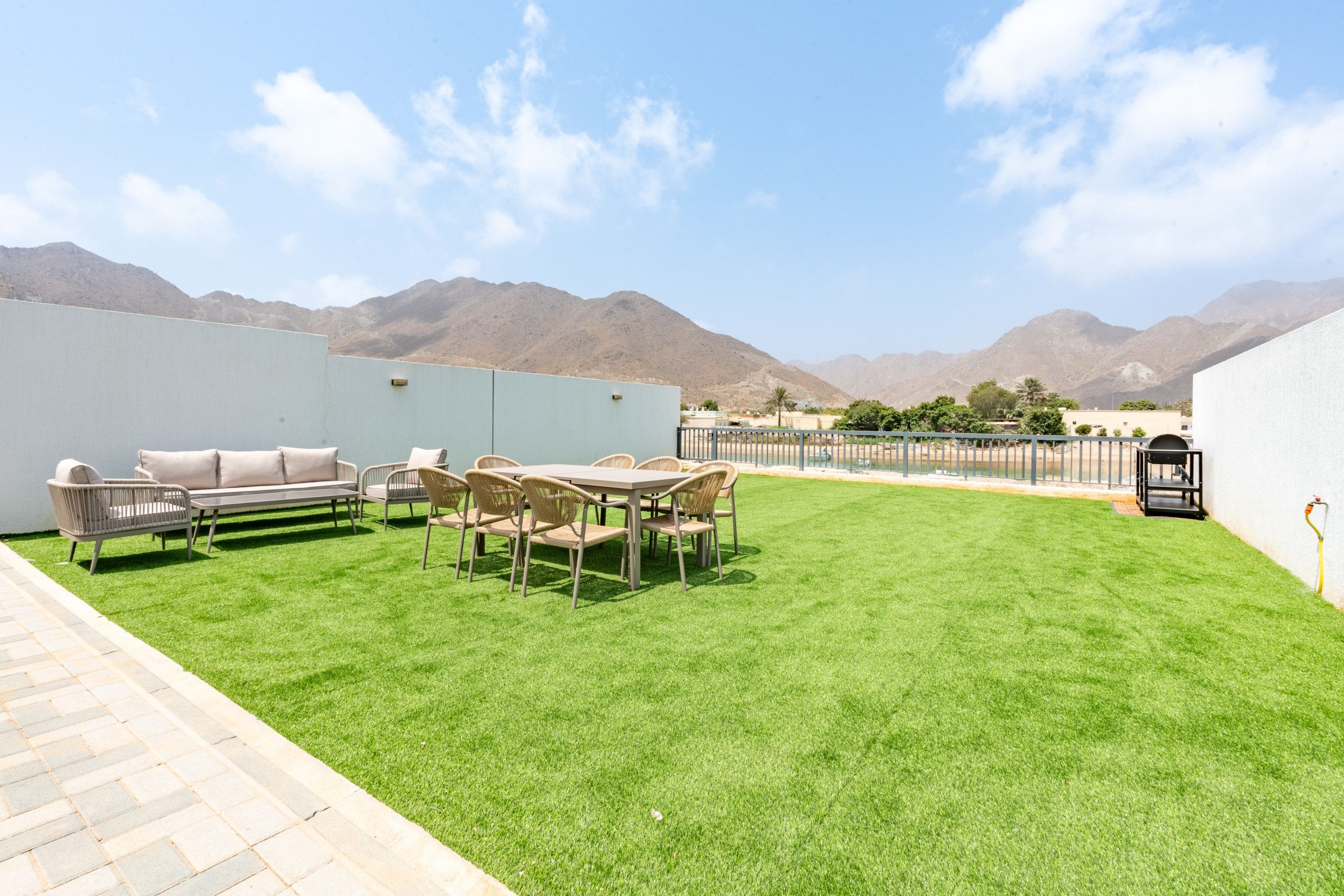Terraza en la azotea con zona de comedor, mobiliario exterior y vistas a las montañas.