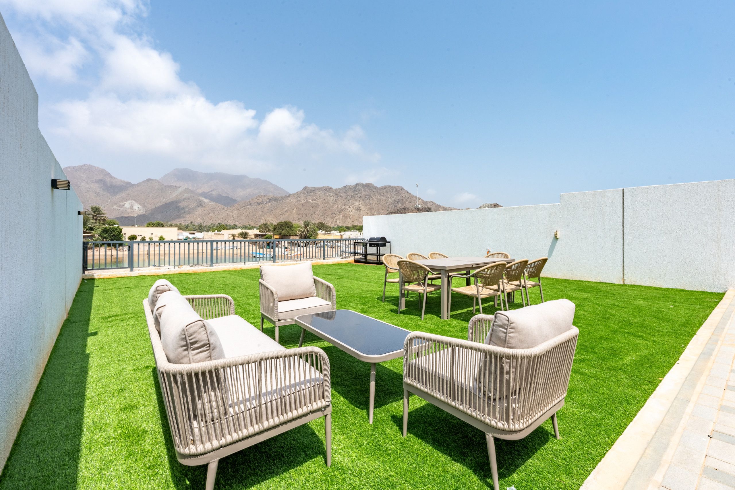 Un patio exterior con césped artificial, mobiliario de mimbre y vistas a las montañas.