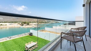 En balkon med udsigt over et kystlandskab, inklusive både og en strand.