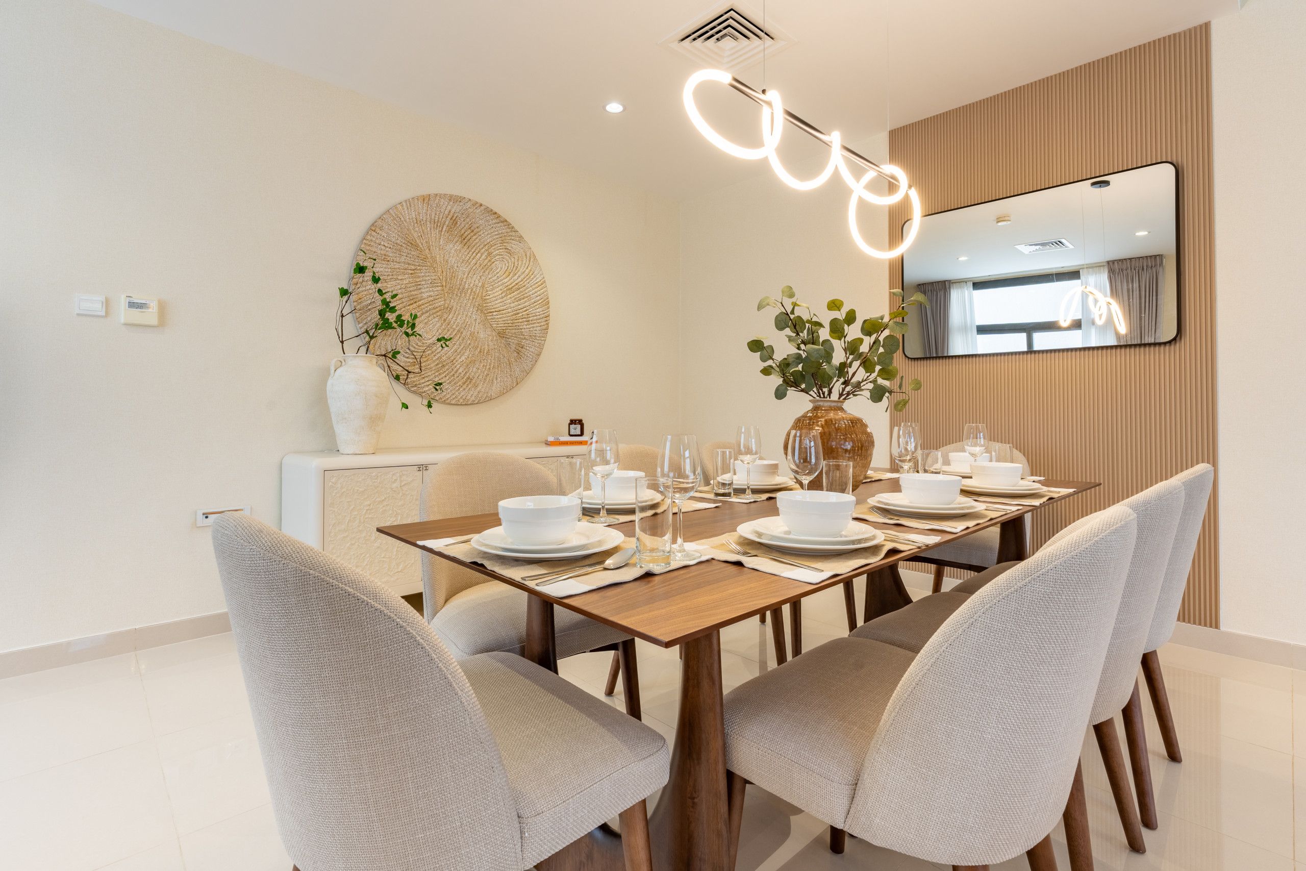 Un comedor moderno con una mesa de madera dispuesta para cuatro personas, rodeada de sillas tapizadas.