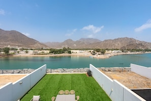 Una terraza con vistas a un cuerpo de agua tranquilo y montañas al fondo.