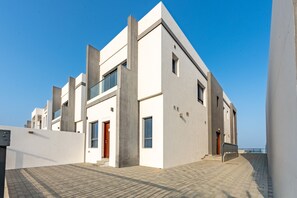 Un bâtiment moderne doté d’un toit plat, de grandes fenêtres et d’un espace d’entrée pavé.