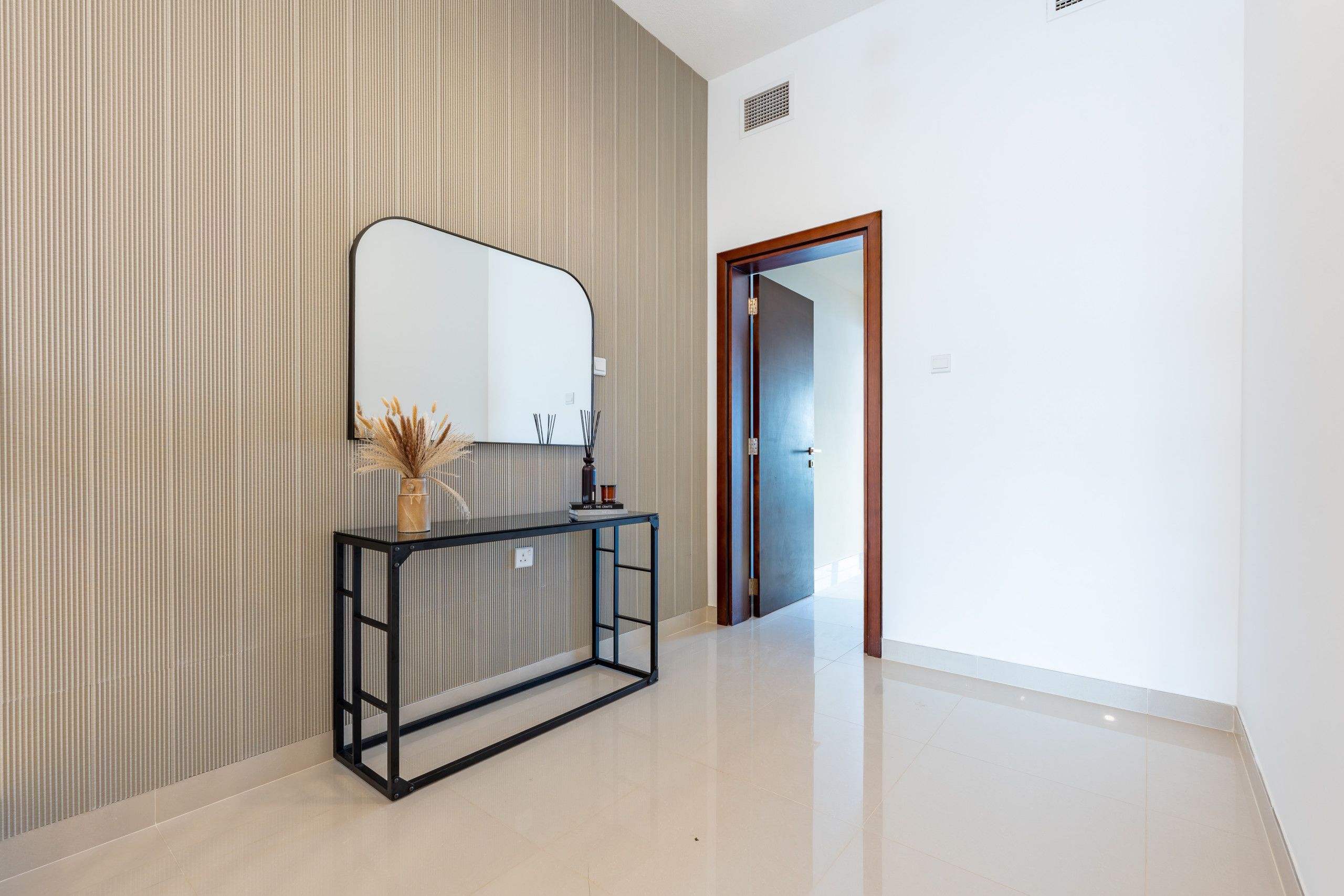 A hallway with a mirrored console table, a radiator, and a door leading to another room.