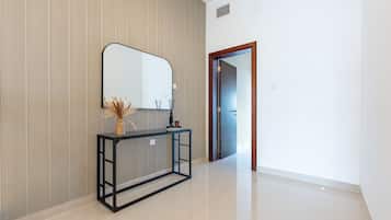 A hallway with a mirrored console table, a radiator, and a door leading to another room.
