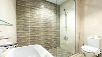 Un baño moderno con ducha envuelta en vidrio, una bañera blanca y un inodoro.