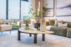 Un salon moderne avec un canapé, des fauteuils, une table basse et une plante décorative.
