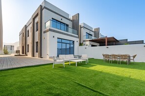 Une maison moderne à deux étages, dotée d’un toit plat, de grandes fenêtres et d’une pelouse bien entretenue.