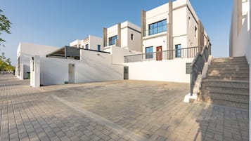 Een modern gebouw met een plat dak, een trap en een verhard pad.