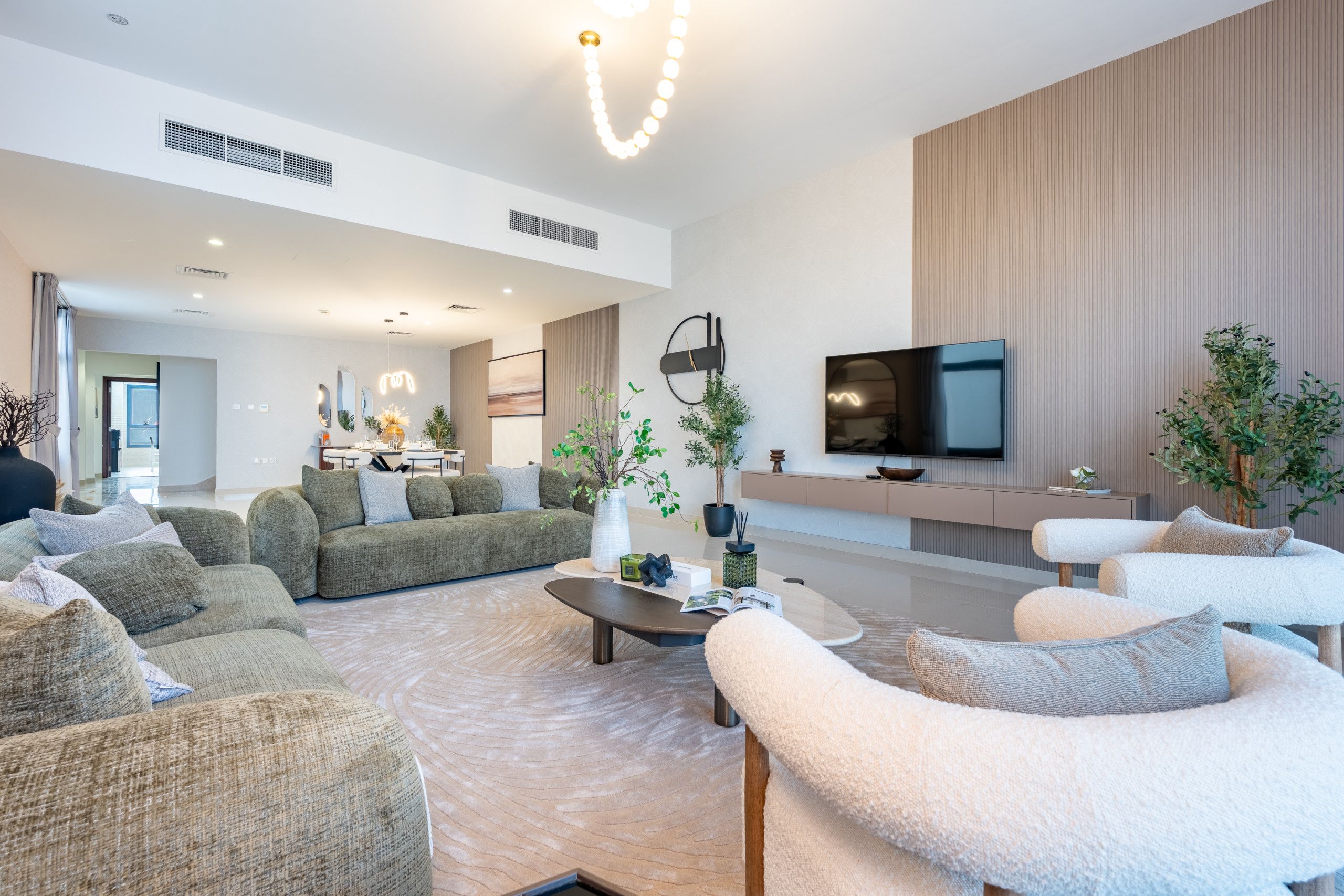 A modern living room with a sofa set, a coffee table, and a flat-screen TV mounted on the wall.