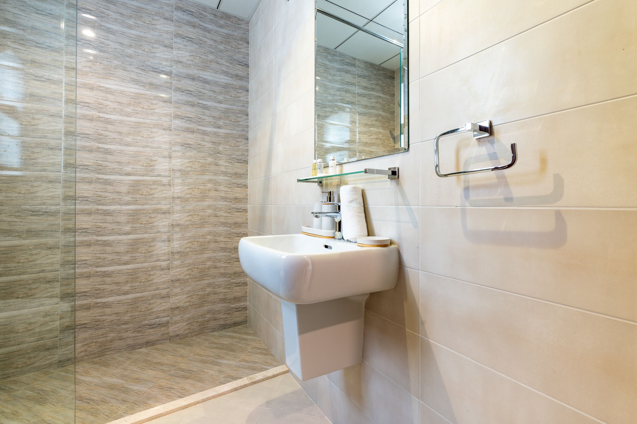 A bathroom with a white sink, a glass shower enclosure, and a mirror.