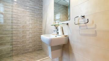 A bathroom with a white sink, a glass shower enclosure, and a mirror.