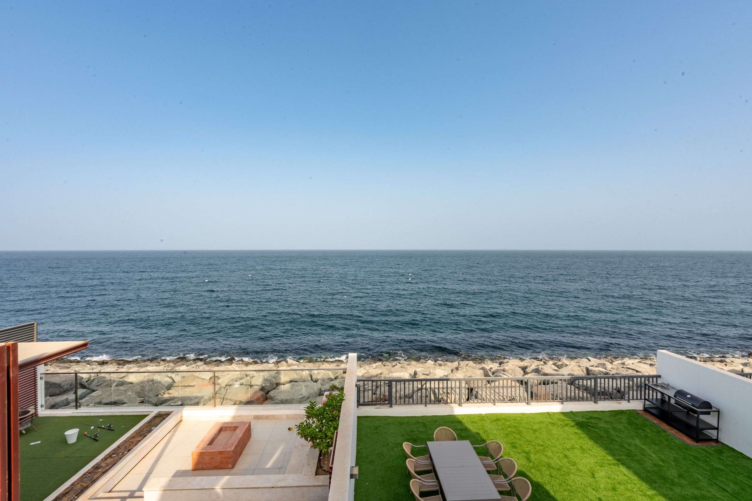 Un patio con vistas al mar, zona de barbacoa y espacio de estar.
