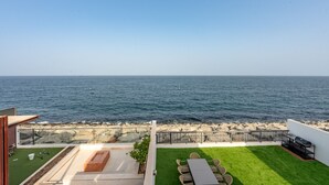 Um pátio com vista para o mar, área de churrasco e espaço para sentar.