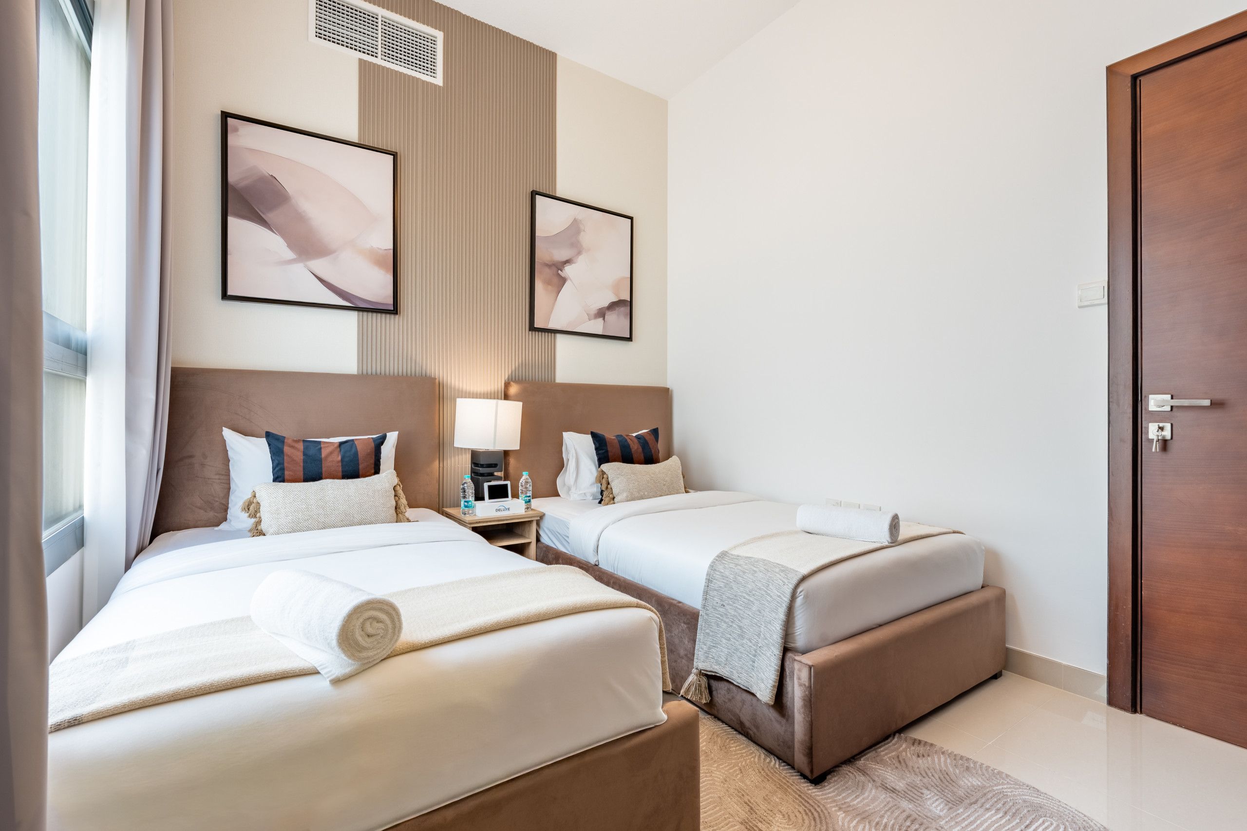 Ein Hotelzimmer mit zwei Betten, einem Nachttisch mit Lampe und einer großen Tür.