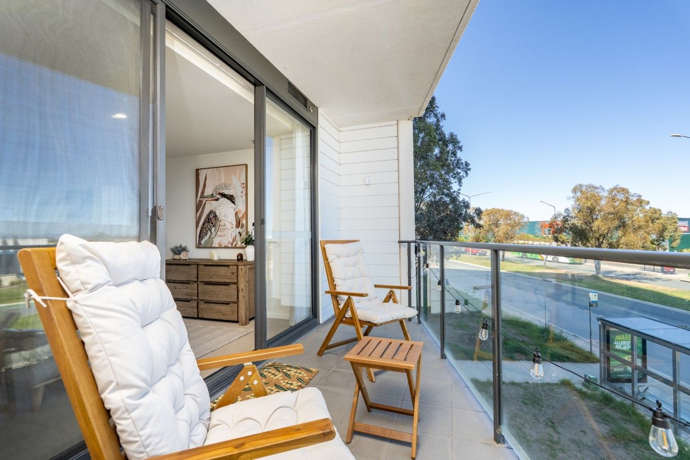 A balcony with a wooden chair, a small table, and a sofa.