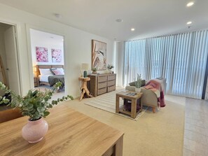 A modern living room with a wooden coffee table, a sofa, a side table with a vase, and a painting on the wall. - Gungahlin 1BR with Balcony, Pool, Gym and Spa (Gungahlin)