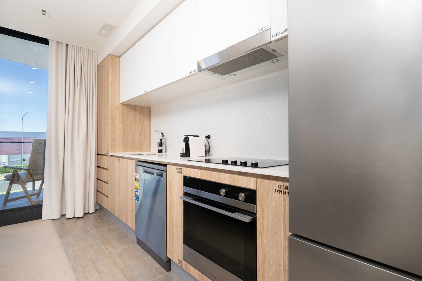 A modern kitchen with a dishwasher, oven, and a stainless steel refrigerator.