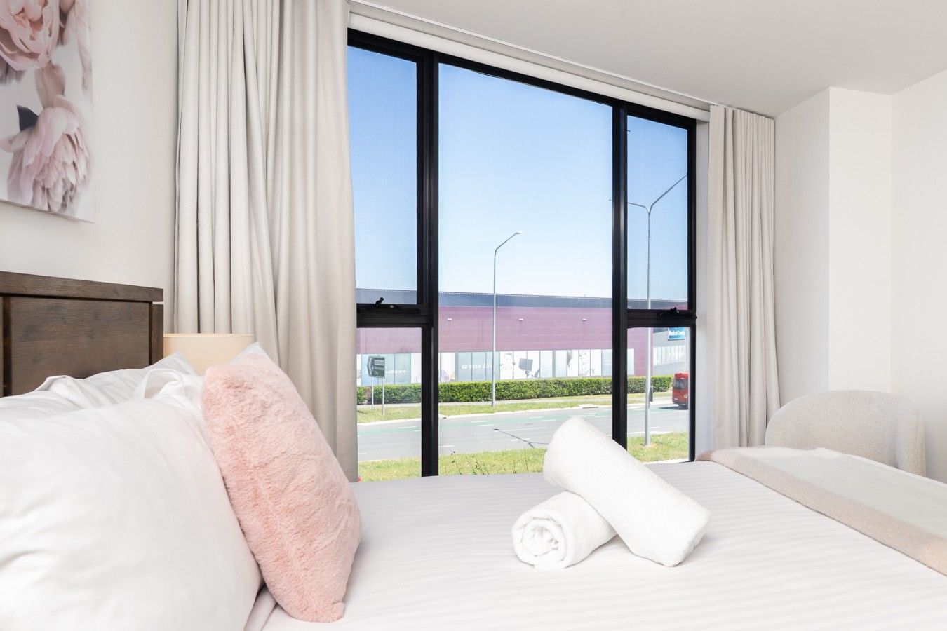 Habitación de hotel con cama, ventana con cortinas y vista a un edificio.