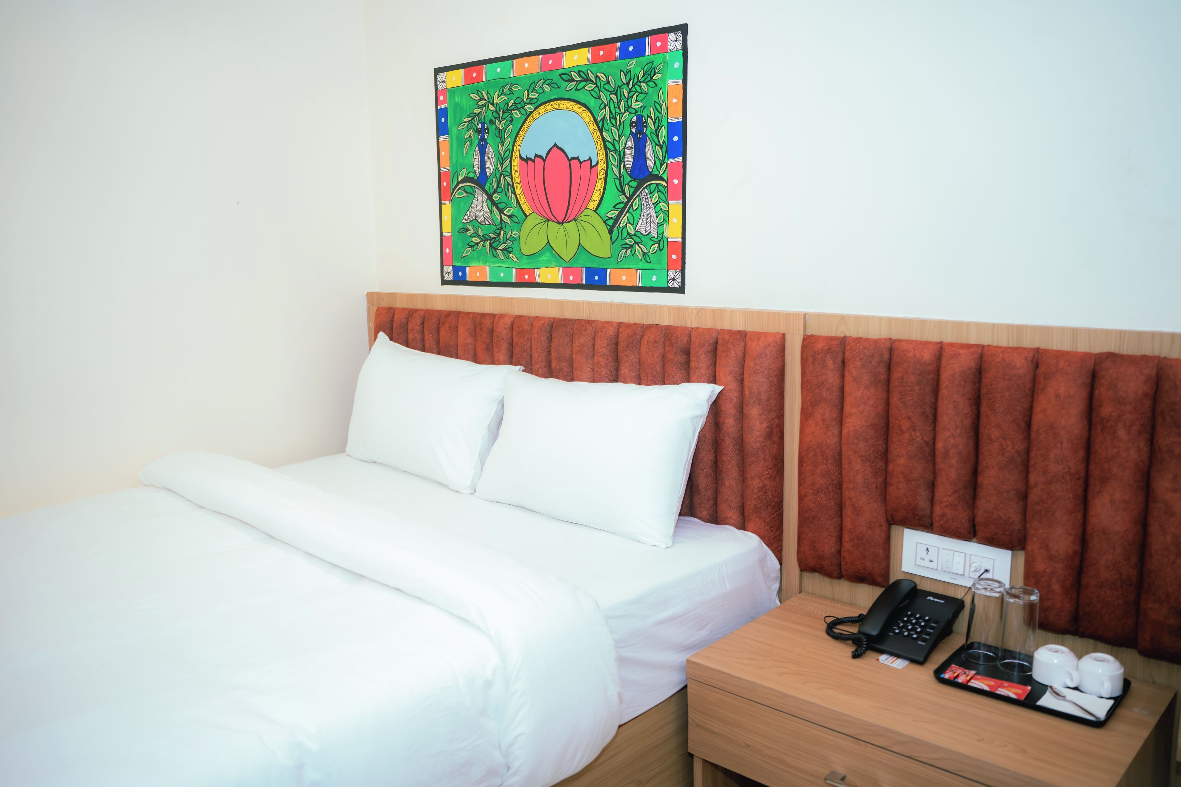 Ein Hotelzimmer mit Bett, Nachttisch, Telefon und Wanddekoration.