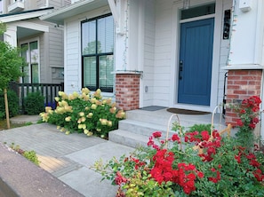 A residential building with a blue front door, a brick column, and a small porch with steps.