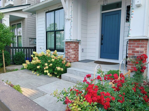 A residential building with a blue front door, a brick column, and a small porch with steps.