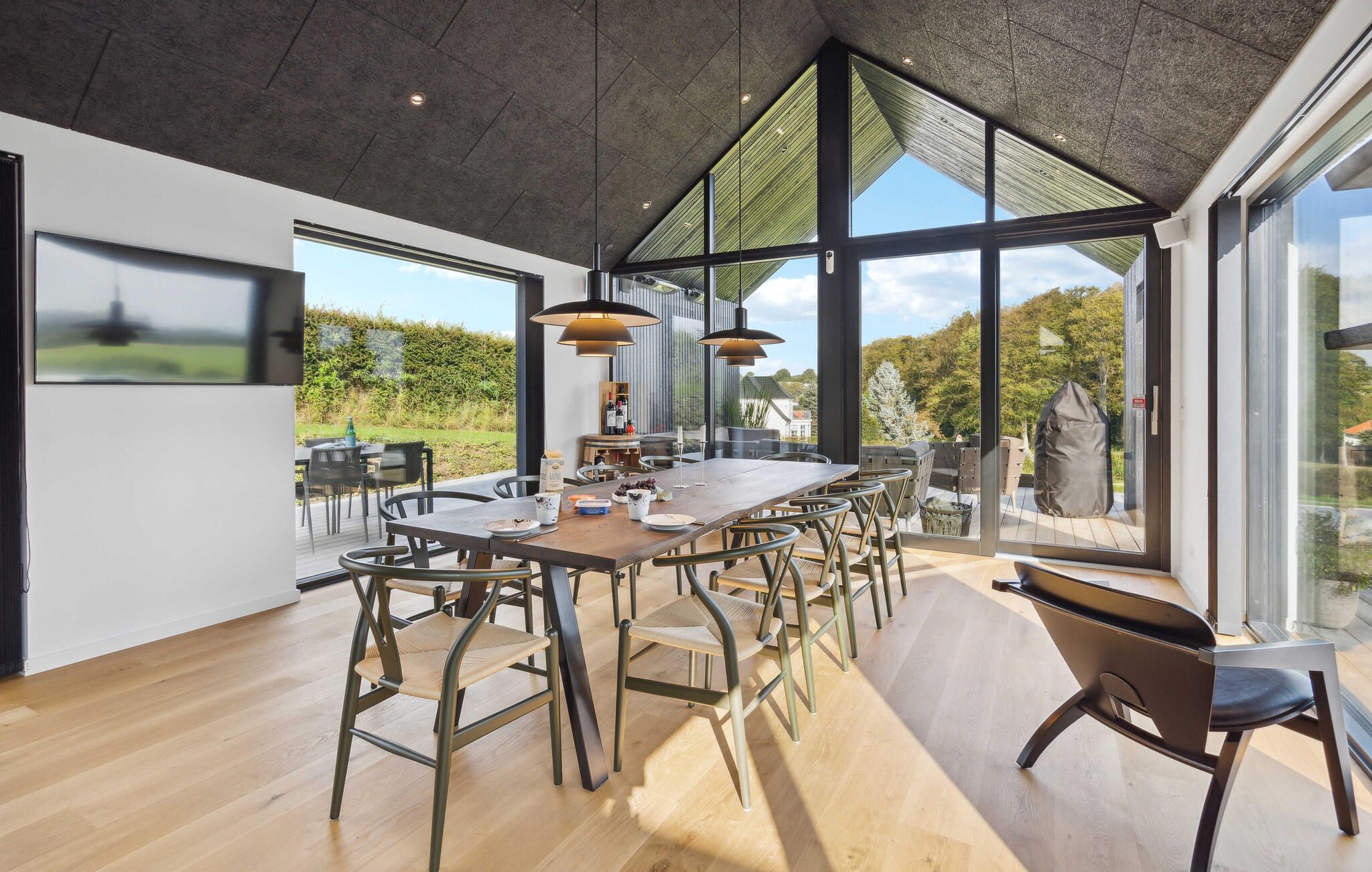 Een moderne eetruimte met een lange tafel, meerdere stoelen en hanglampen.