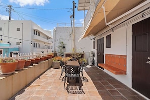 A narrow outdoor patio with a table and chairs, surrounded by potted plants and a white fence. - Vida Luna | Cozy Old San Juan Retreat + Terrace (San Juan)
