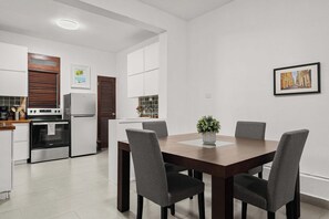 A modern kitchen with a dining area, featuring a table with chairs, a small potted plant, and a framed picture on the wall. - Vida Luna | Cozy Old San Juan Retreat + Terrace (San Juan)