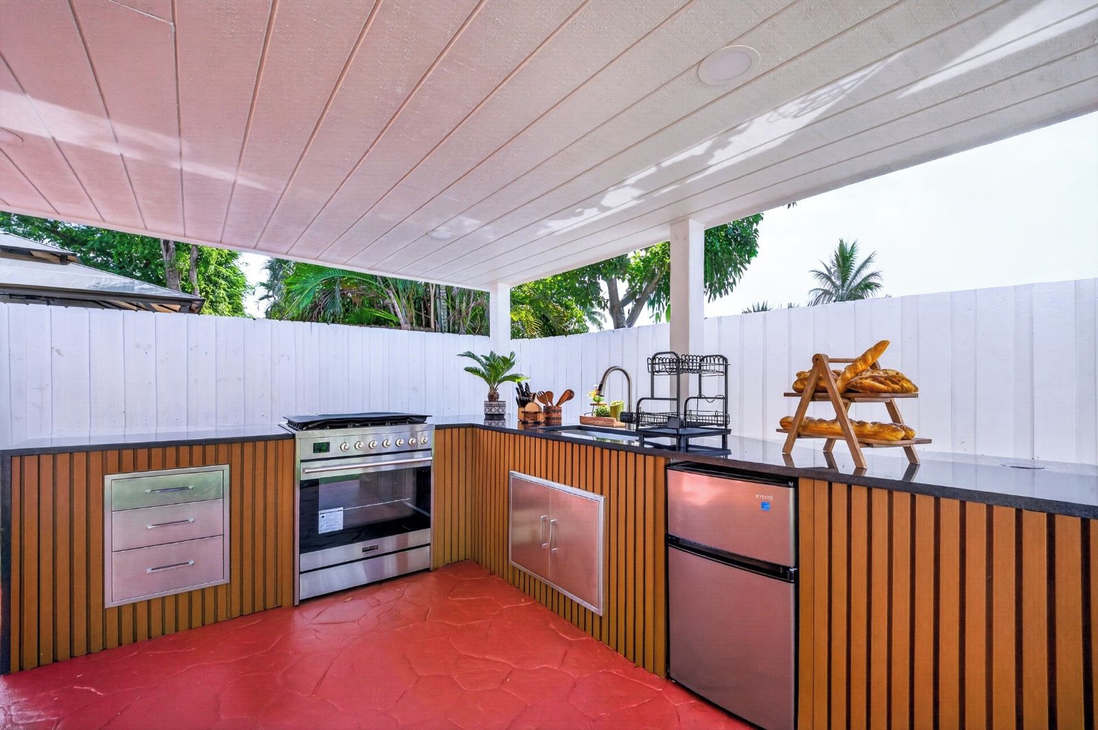 A compact outdoor kitchen with a built-in oven, a refrigerator, and a sink.