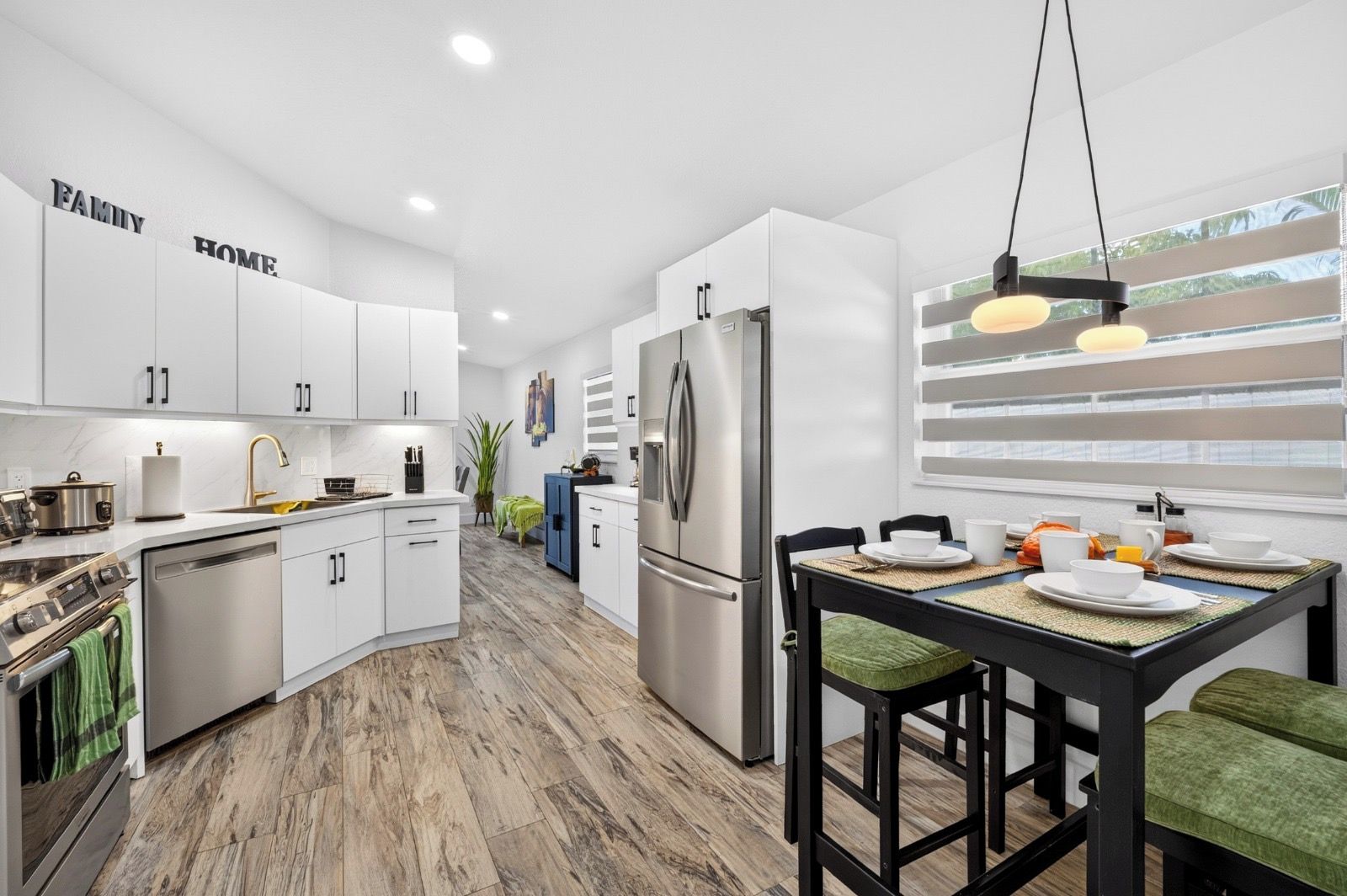 A modern kitchen with white cabinetry, stainless steel appliances, and a dining area with a table set for two.