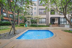 A residential building with a swimming pool, surrounded by trees and greenery. - Noma by Kozystay - Alam Sutera (Tangerang Selatan)